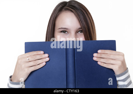 young woman peering over a hard back book Stock Photo