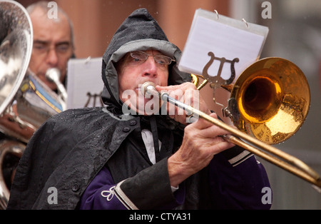 Visually impaired rain on glasses of musician trombone player in brass band trying to read music Stock Photo