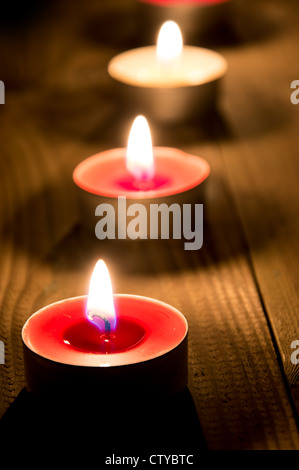 A line of burning candles on wooden background Stock Photo