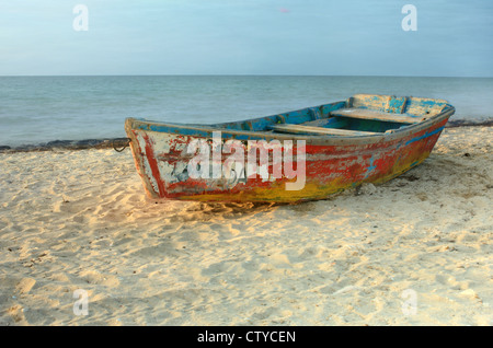 Solo rowboat with peeling paint resting on sandy beach in Progreso, Yucatan, Mexico Stock Photo