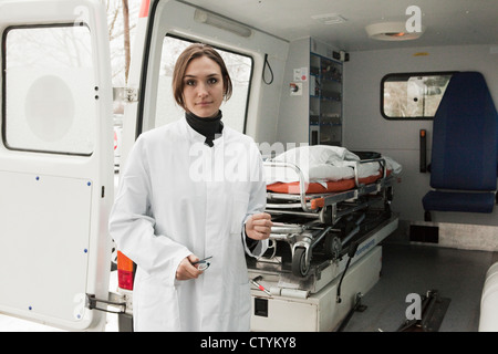 Young female doctor stands near ambulance Stock Photo