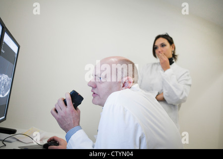 Radiologist  and a female colleague examines  MRI scan on monitor Stock Photo