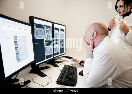 Radiologist  and a female colleague examines  MRI scan on monitor Stock Photo