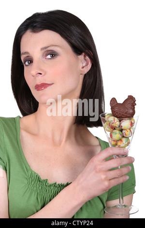 Woman holding a glass full of mini chocolate eggs Stock Photo