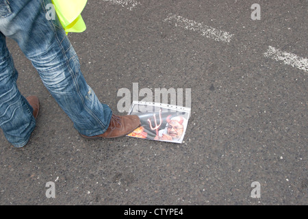 Pro Assad demonstration in Berlin. An Assad loyalist stamps on a picture showing  Yusuf al-Qaradawi. Stock Photo