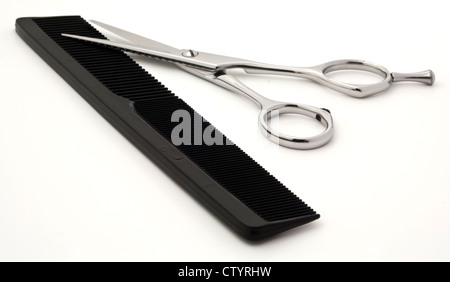 Close up of shiny silver hair cutting scissors or shears and black comb isolated on white background with copy space. Stock Photo