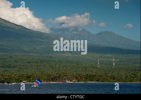 A Balinese fishing boat under sail in the Jemeluk area of Amed, Bali, Indonesia. The volcano Mt. Agung is in the background. Stock Photo