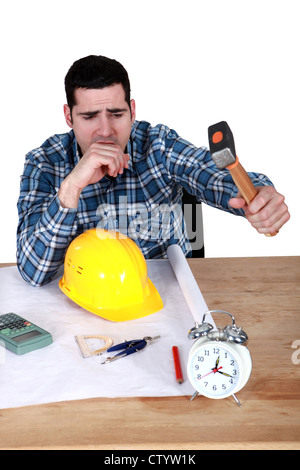 Engineer hitting an alarm clock with a hammer Stock Photo