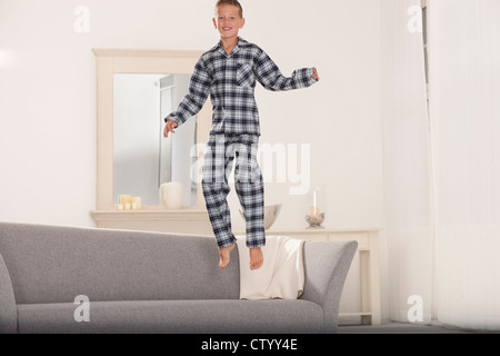 Boy in pajamas jumping on couch Stock Photo