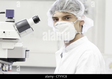 Scientist standing at microscope in lab Stock Photo