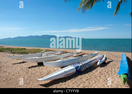 Outrigger canoes resting on the beach of The Strand at Townsville with view of Magnetic Island across the Coral Sea Stock Photo