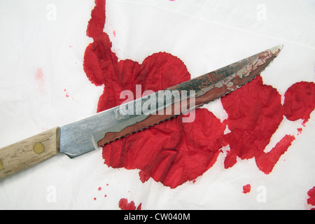 A simulated serrated edged bloodied knife on a simulated blood covered white cloth. Stock Photo