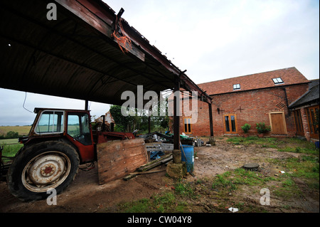 A barn conversion with an old tractor from the original farm in progress Warwickshire, UK Stock Photo