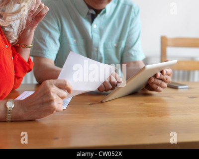 Older couple reading mail in kitchen Stock Photo