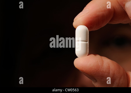 A patient with polycystic kidney disease holds a Vicodin 5/500 m tab, Hydrocodone APAP, a prescribed pain medication. Stock Photo