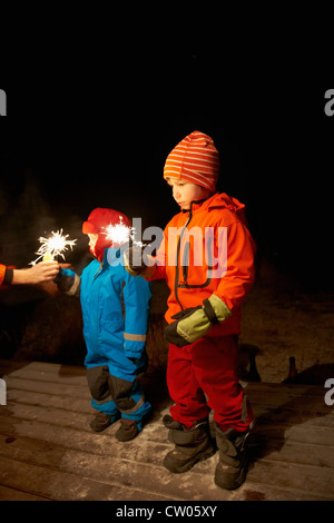 Boys playing with sparkler outdoors Stock Photo