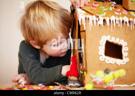 Boy decorating gingerbread house Stock Photo