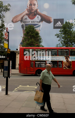 A man walks near the inspiring image of Team GB gold medallist heptathlete Jessica Ennis and diver Tom Daley which adorns the exterior of the Adidas store in central London's Oxford Street, during the London 2012 Olympic Games. The ad is for sports footwear brand Adidas and their 'Take The Stage' campaign which is viewable across Britain and to Britons who have been cheering these athletes who have been winning medals in numbers not seen for 100 years. Stock Photo