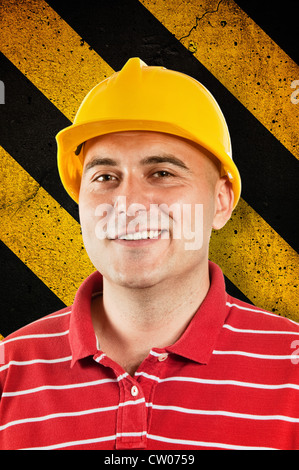 Young construction worker in red shirt wearing yellow hard hat safety equipment. Stock Photo