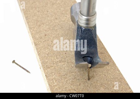 Hammer pulling a nail out of a length of wooden board Stock Photo