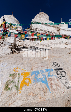 White-washed stone wall and chortons at Shey Monastery with stings of brightly colored prayer flags and religious rock writings. Stock Photo