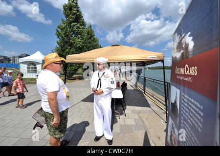 Gunner's Mate 1st Class Dennis Luis talks to a tourist while visiting the Cyclone-class coastal patrol ship USS Hurricane (PC 3). Hurricane, the Oliver Hazard Perry-class frigate USS DeWert (FFG 45), and the Royal Canadian Navy Halifax-class frigate HMCS Ville de Quebec (FFH 332) are visiting cities in America and Canada to commemorate the Bicentennial of the War of 1812. Stock Photo