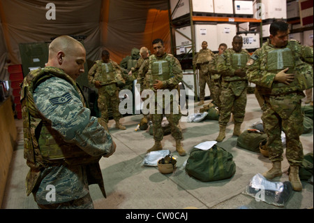 Staff Sgt. Seth Tuggle demonstrates how to properly wear a tactical vest to transient Airmen during equipment distribution at the Transit Center at Manas, Kyrgyzstan, Aug. 4, 2012. The Transit Center's Expeditionary Theater Distribution Center equipment technicians assist transiting personnel daily on how to properly wear individual protective gear. Tuggle is a Transit Center ETDC equipment technician deployed out of Little Rock Air Force Base, Ark. and is a native of Morton, Ill. Stock Photo