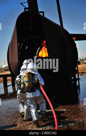 Firefighters with the 2th Special Operations Civil Engineer Squadron enter the burn pit at Cannon Air Force Base, N.M., Aug. 2, 2012. The pit houses a replicated aircraft equipped with a propane tank and several igniters used to sustain training fires. Stock Photo