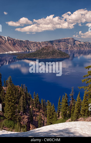 Afternoon clouds and Wizard Island reflect in the calm water of Oregon’s Crater Lake National Park. Stock Photo