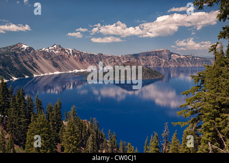 Afternoon clouds and Wizard Island reflect in the calm water of Oregon’s Crater Lake National Park. Stock Photo