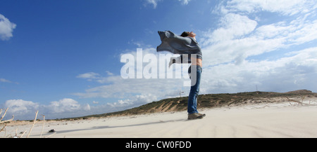 Woman standing on windy beach Stock Photo