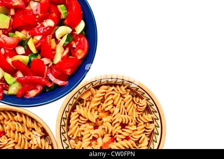A bowl of salad and two plates with pasta with tomatoes, isolated on white background Stock Photo
