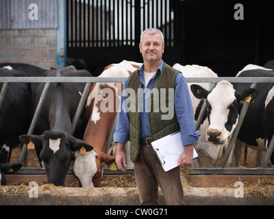 Farmer standing by cows in barn