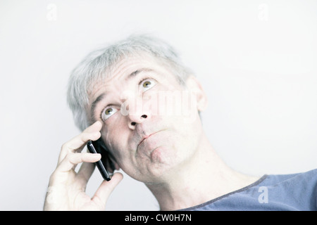 Frowning man talking on cell phone Stock Photo