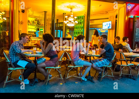Romantic Paris, France,Young Couples drinking, Eating in Paris Café, Bistro Restaurant, 'Café Le Bistro' in the Canal Saint Martin Area, Outside on Terrace, Night, women dining sidewalk terrasse, lights, french woman paris cafe, french woman paris bistrot, Young adults on holiday Stock Photo