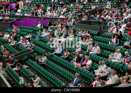 Crowds watch in Centre Court as the Tennis events at the London 2012 Olympics take place at Wimbledon. Empty seats. Stock Photo