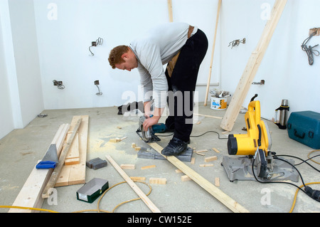 Builders using a sander on a plank of wood. Stock Photo