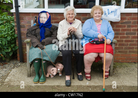 Effigy of The Queen sat on bench with two elderly ladies during Scarecrow Day in village of Brampton Bryan Herefordshire England UK Stock Photo