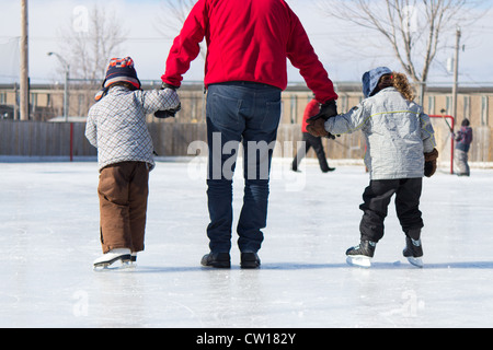 Family having fun at the outdoor skating rink in winter. Stock Photo