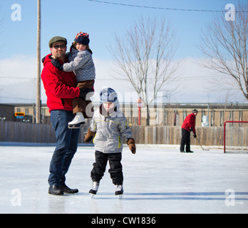 Father with son and daughter playing at the skating rink in winter. Stock Photo