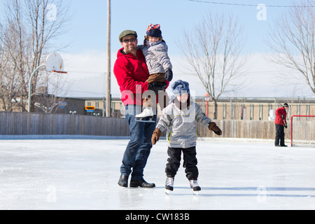 Father with son and daughter playing at the skating rink in winter. Stock Photo