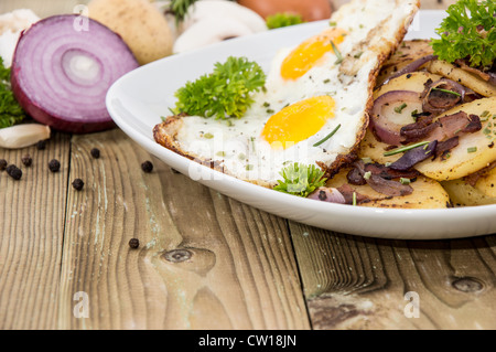 Fried Egg on a heap of roasted Potatoes on wooden background Stock Photo