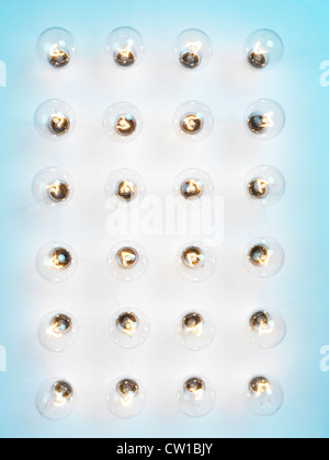 Array of lit incandescent tungsten light bulbs on blue background Stock Photo