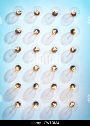 Group of lit incandescent tungsten light bulbs isolated on blue background Stock Photo
