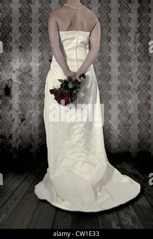 a woman in a white dress holding a bouquet of roses behind her back Stock Photo