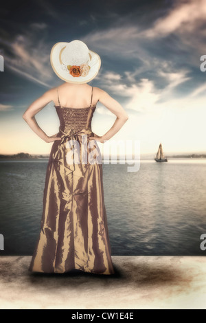 a woman in an elegant vintage dress on the shore of a lake Stock Photo