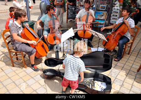 Busking cello players - four young men - performing outdoors on a warm summer day, in the town of Amboise, Indre-et-Loire, central France. Stock Photo