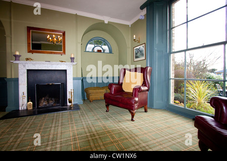 georgian style living room with fireplace and old leather armchair Stock Photo