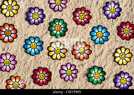 Multicoloured embroidery iron on Smiley face flower patch in sand on a beach Stock Photo