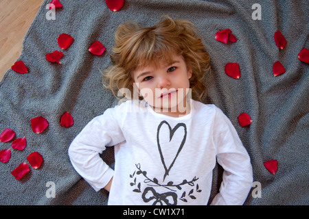 Blonde baby girl with rose petals Stock Photo